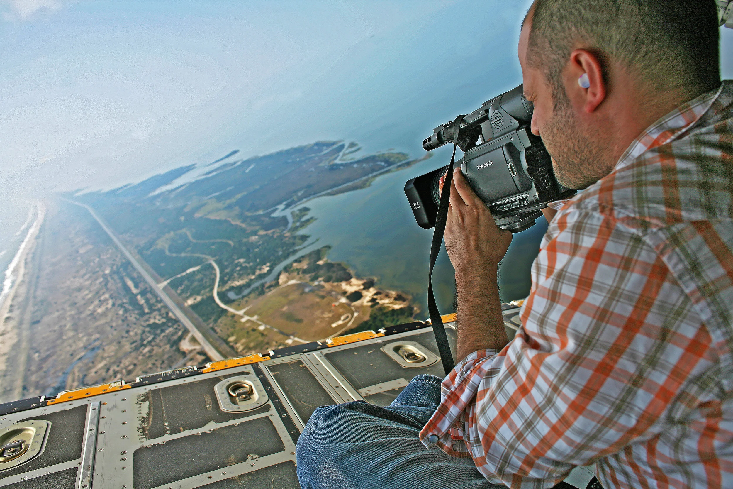 Brian shooting hurricane damage from the cargo hatch of a Coast Guard C-130 aircraft