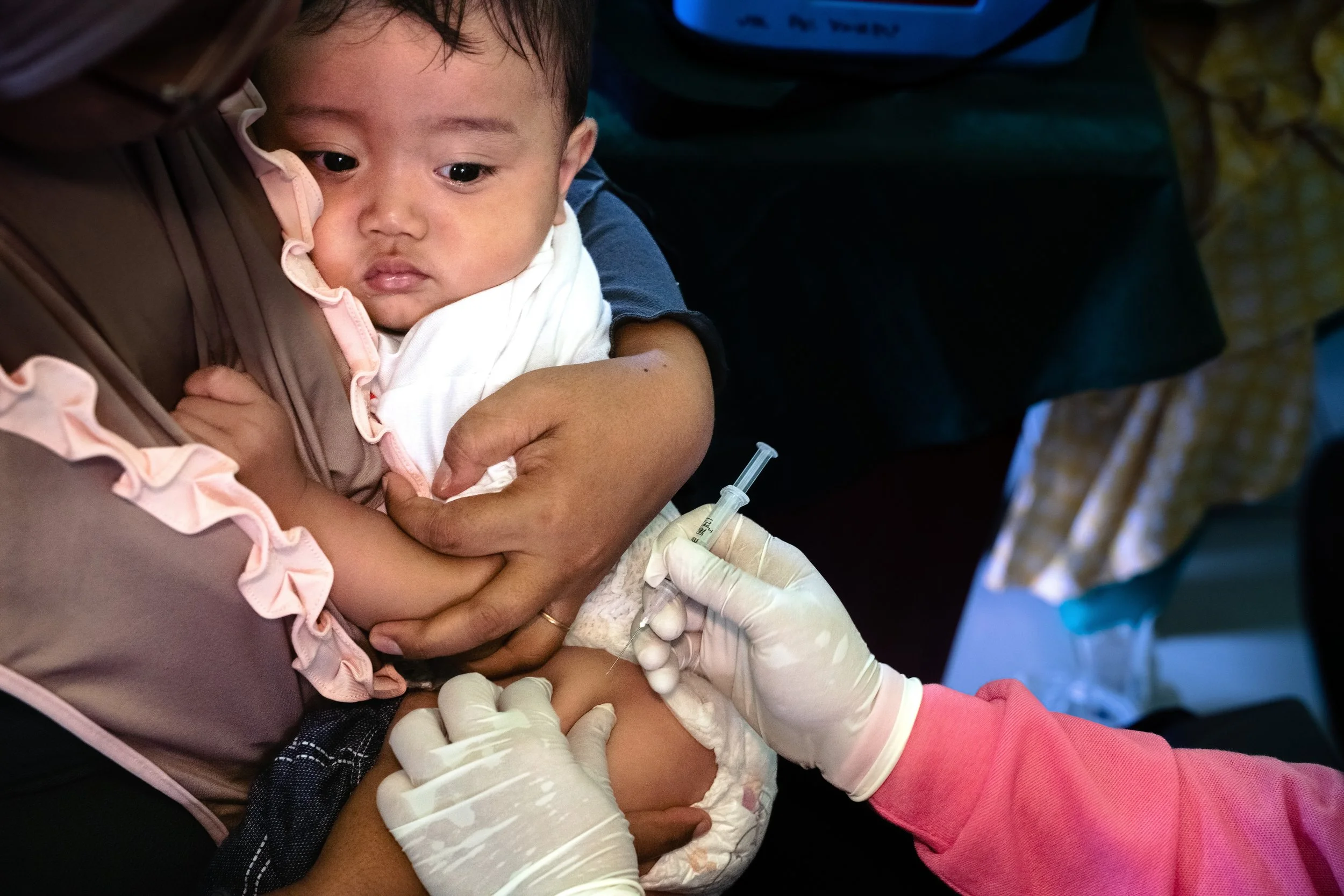 10-month-old Vito at a village health clinic receives his childhood immunizations outside of Tanjung Pinang, Riau Islands Province during National Childhood Immunization Month (BIAN).