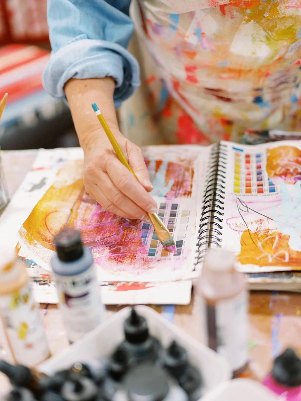 Hands painting a page in an art journal