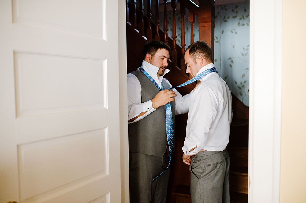 Groomsman tying groom's tie