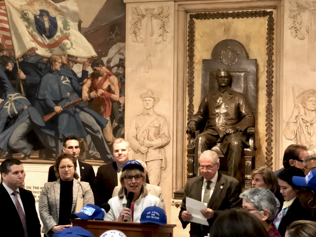 Senate President Karen Spilka speaks at a ceremony celebrating the passage of Lift the Cap on Kids, while Speaker DeLeo, sponsors Senator DiDomenico, Chairwoman Decker, and other legislators look on.