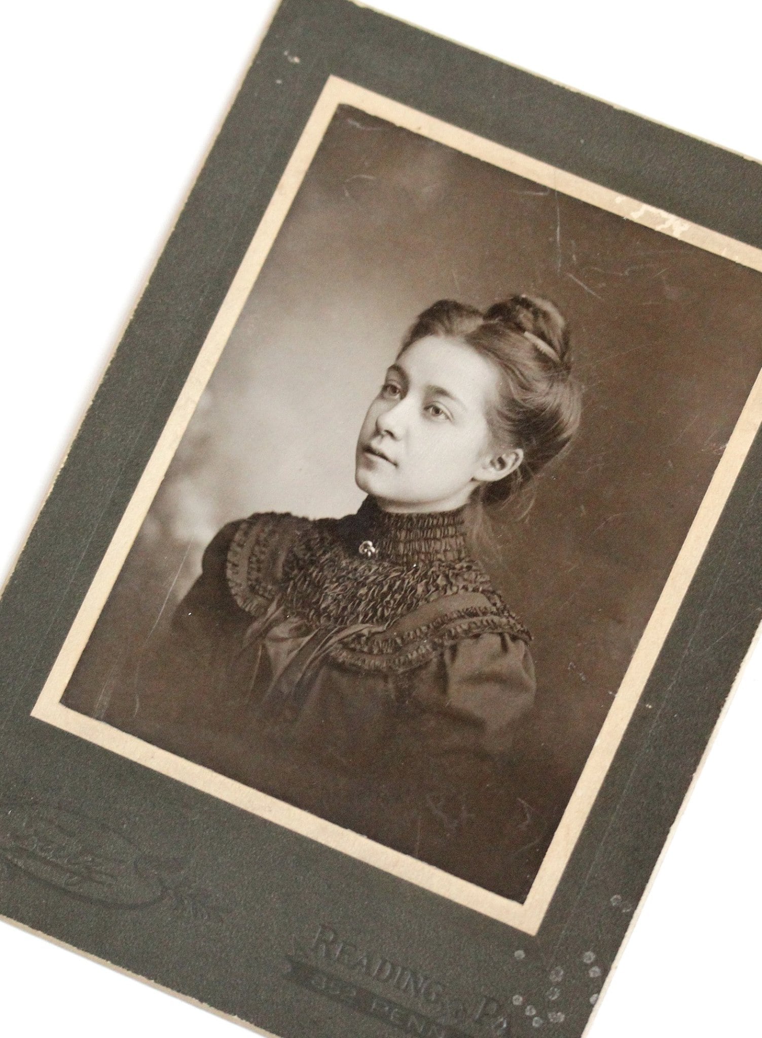 Victorian era cabinet card from Reading, Pennsylvania depicting a somber young lady wearing a large love knot. 