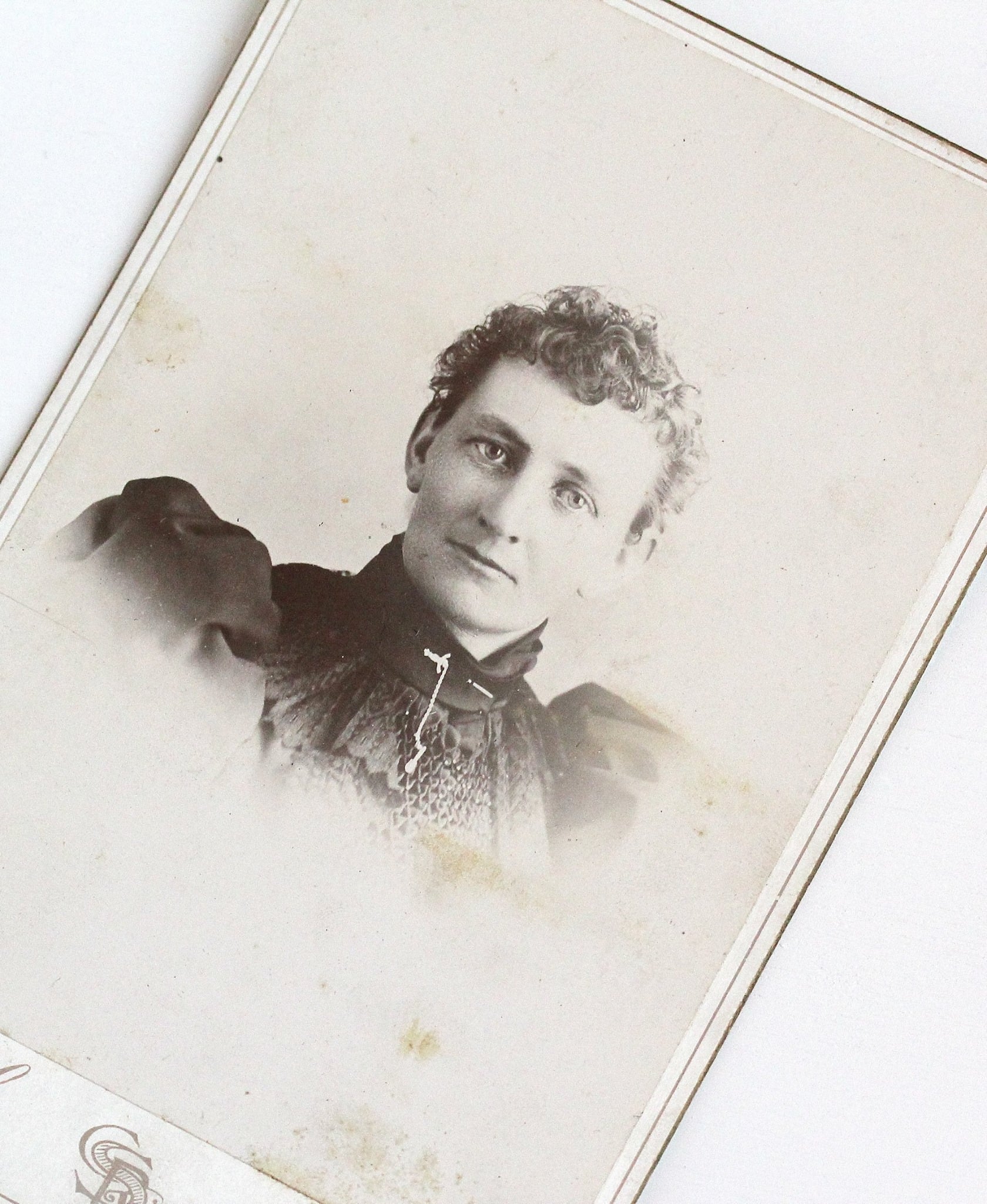 Victorian era cabinet card with a long description on the back of the woman pictured (Lillie Smith) and her long family line. She is shown wearing an almost masculine sword brooch with chain. 