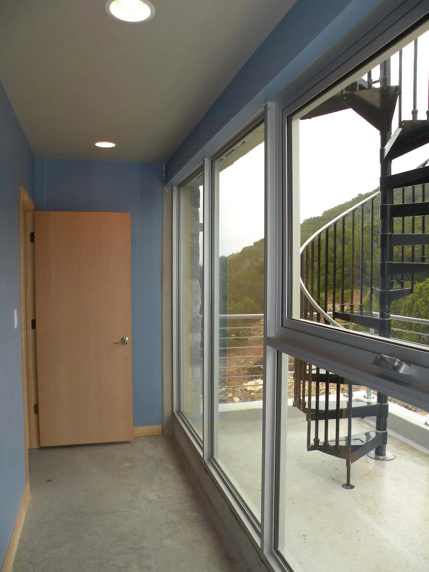 Third level hallway/ gallery, with view to spiral stair leading to roof deck. 