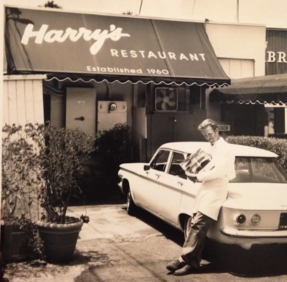 Harry III poses with a customer's classic Corvair in front of the shop.