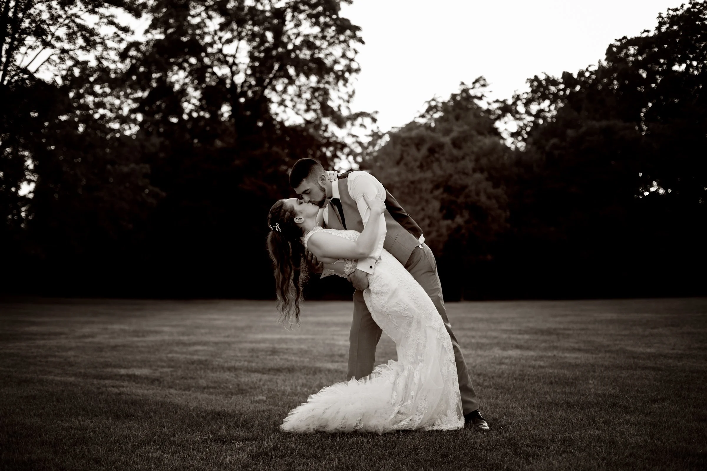 Black and white photo of groom dipping bride with kiss | Outdoor wedding photos | Romantic weddings in michigan | Mid michigan wedding photography
