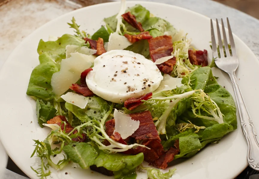 Frisée and Bibb lettuce salad with a poached egg, bacon, croutons, shaved parmesan and warmed sherry vinaigrette.