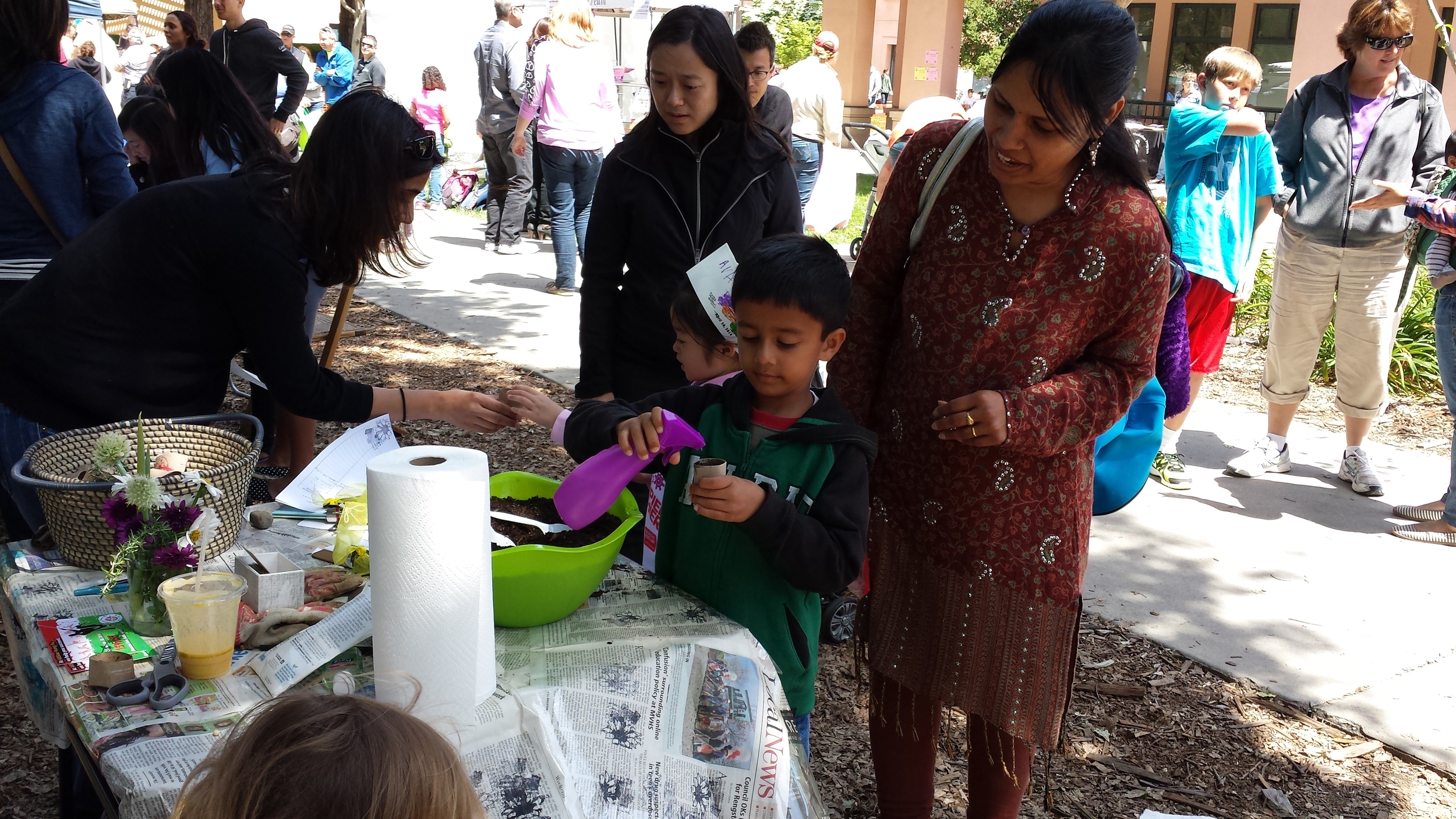 Kids planting snap peas in little containers made from toilet paper roll inserts.