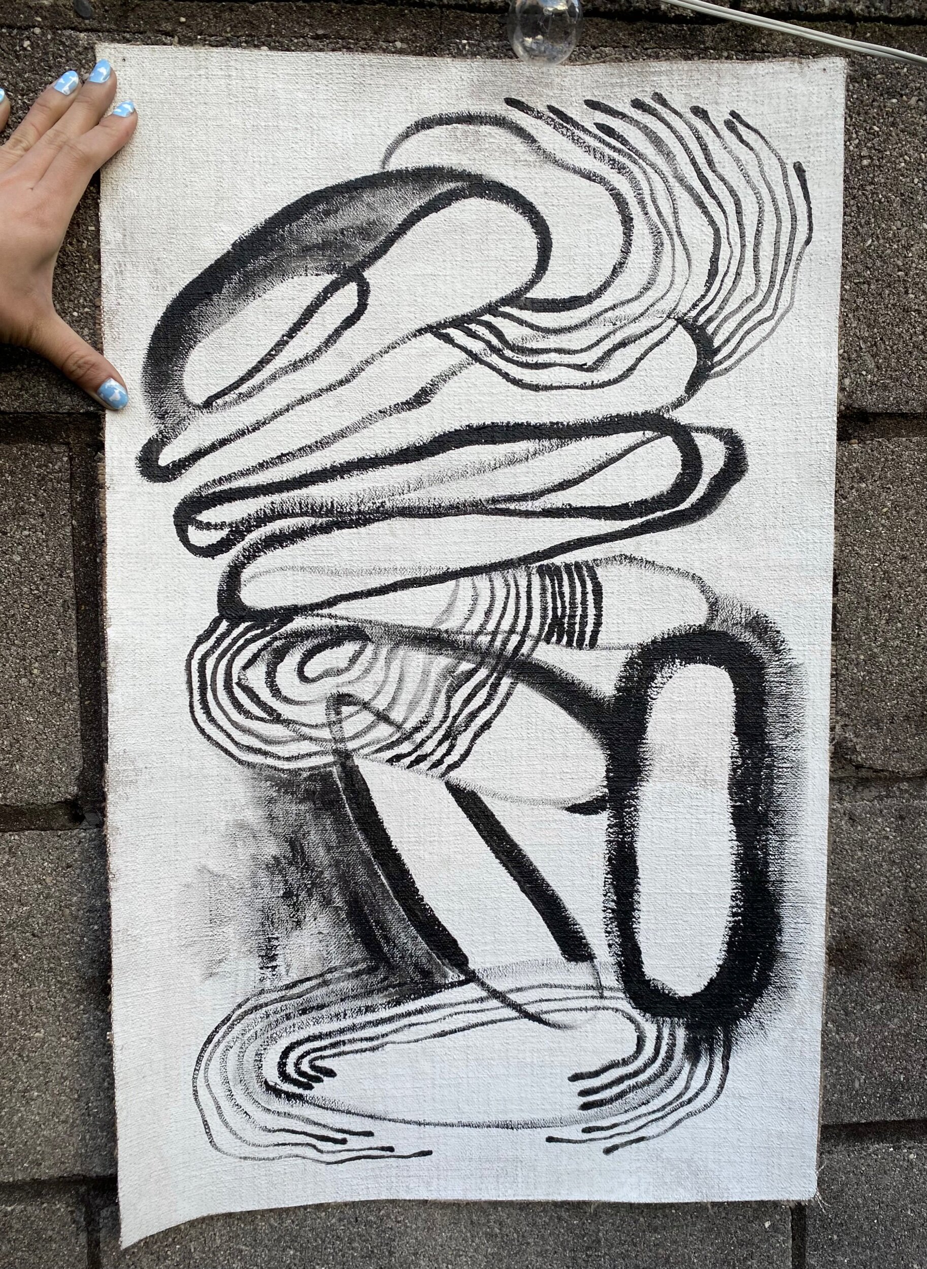 Person holding a black and white painting in a patio