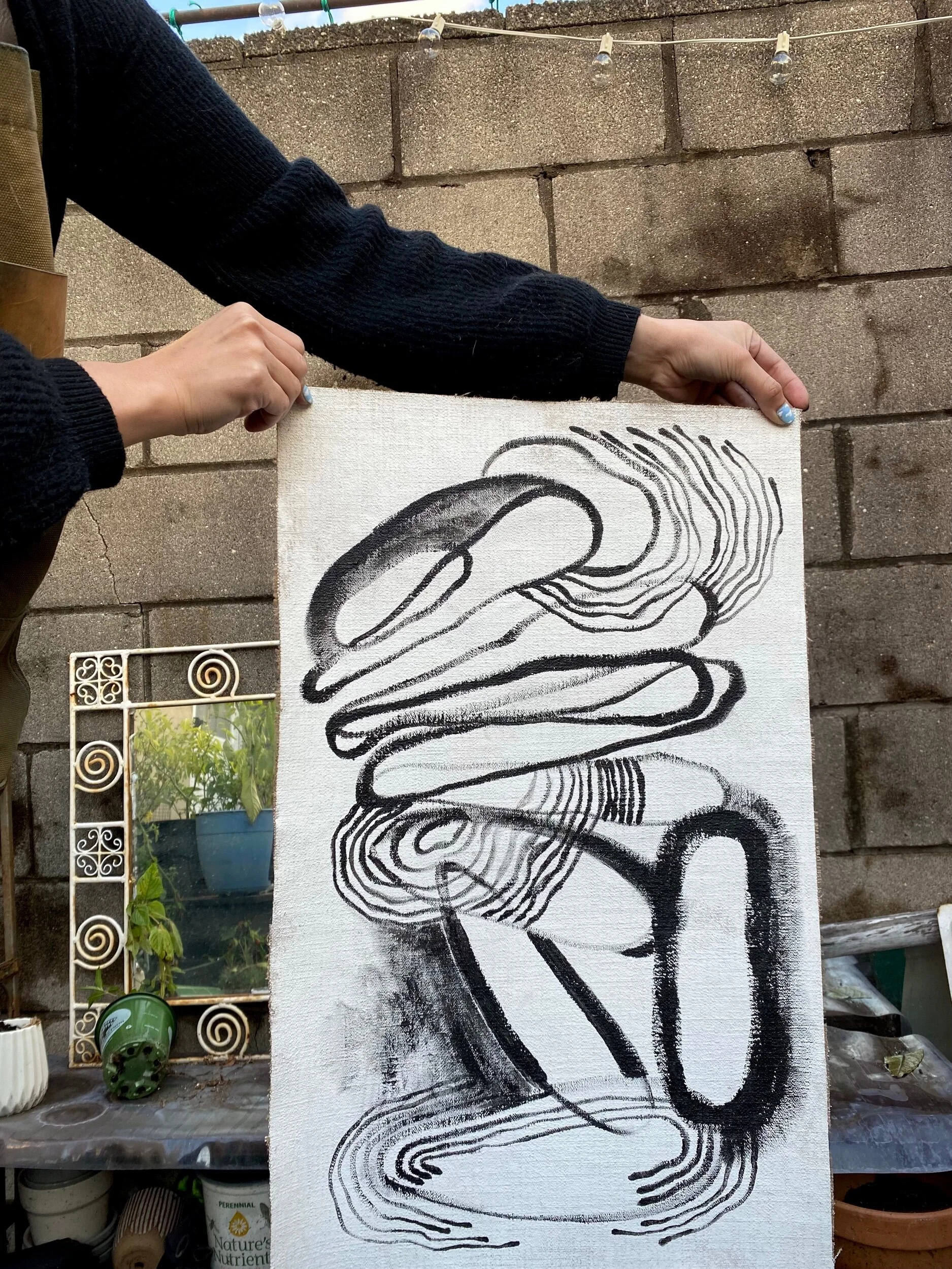 Person holding a black and white painting in a patio