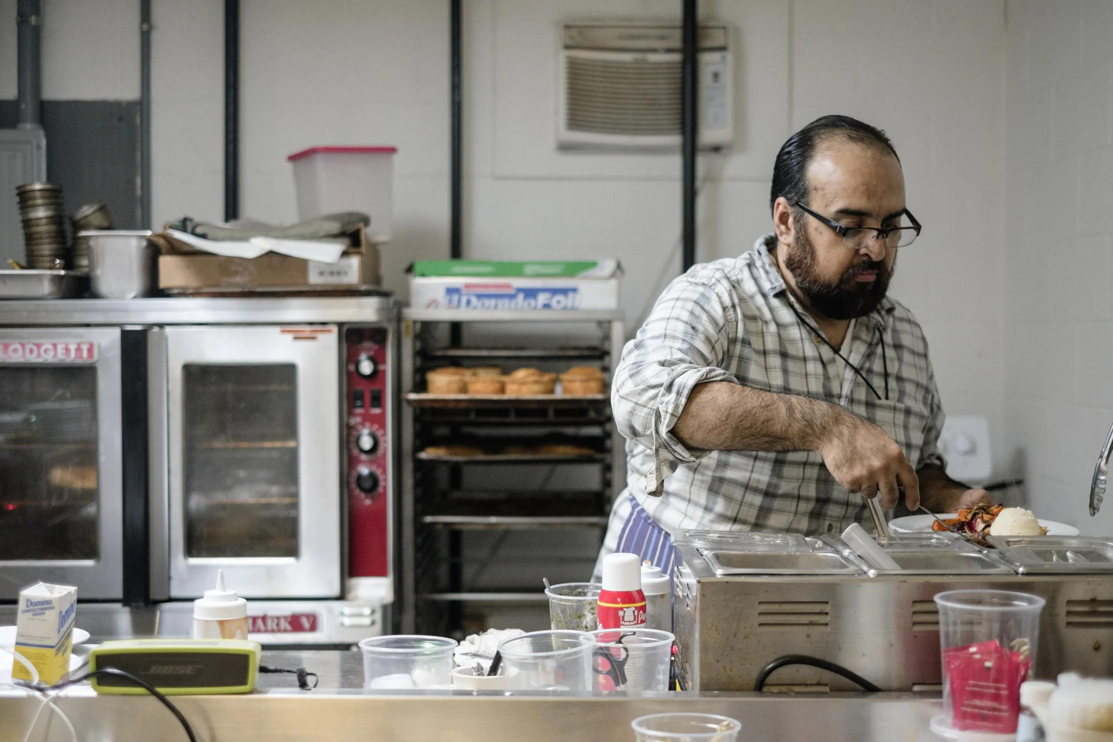  A kitchen staff member serves some mash and seasonal vegetables. 