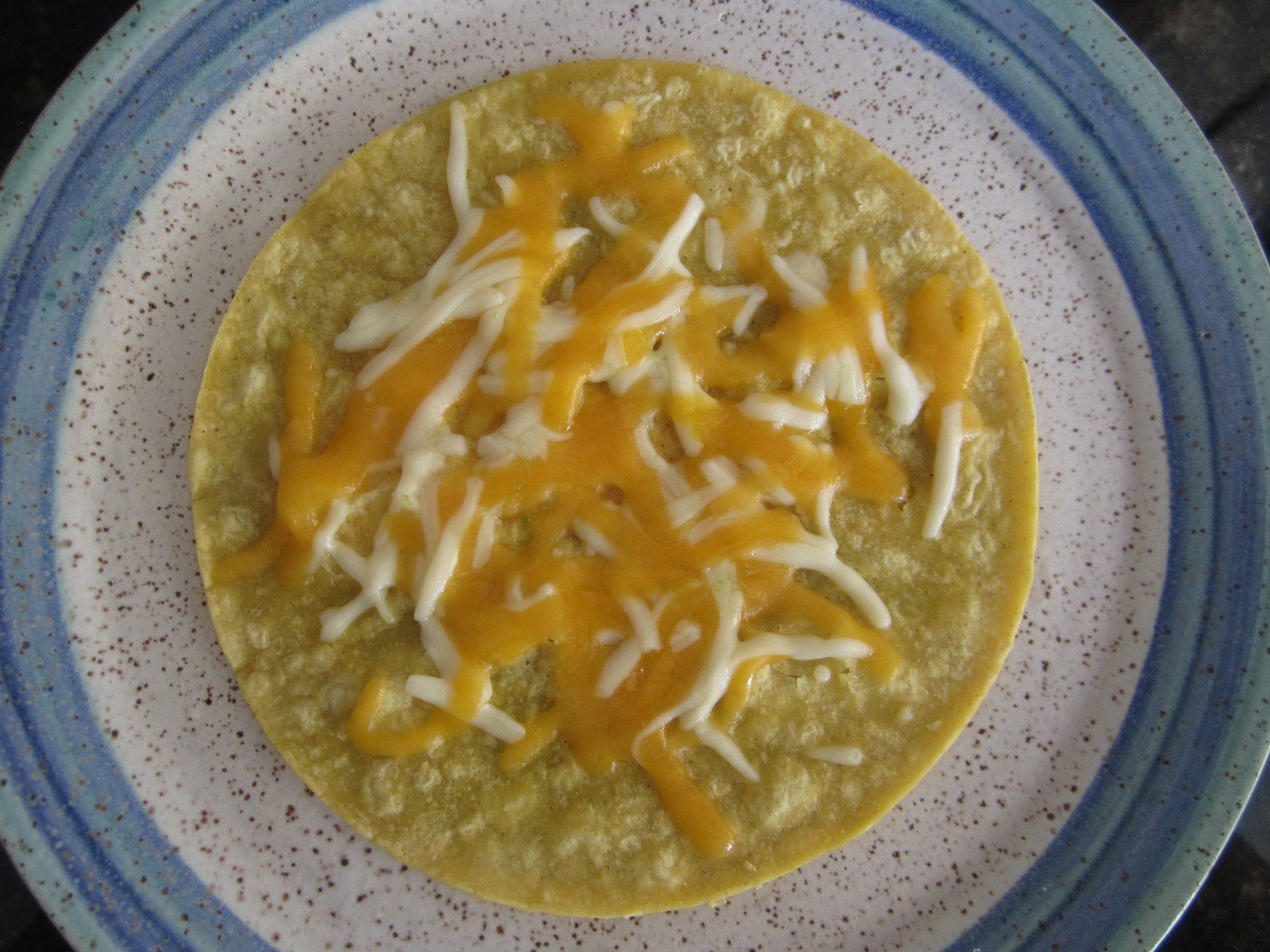 Melt part of the cheese on the first tortilla, remove it from the skillet, and set it aside for a moment. 