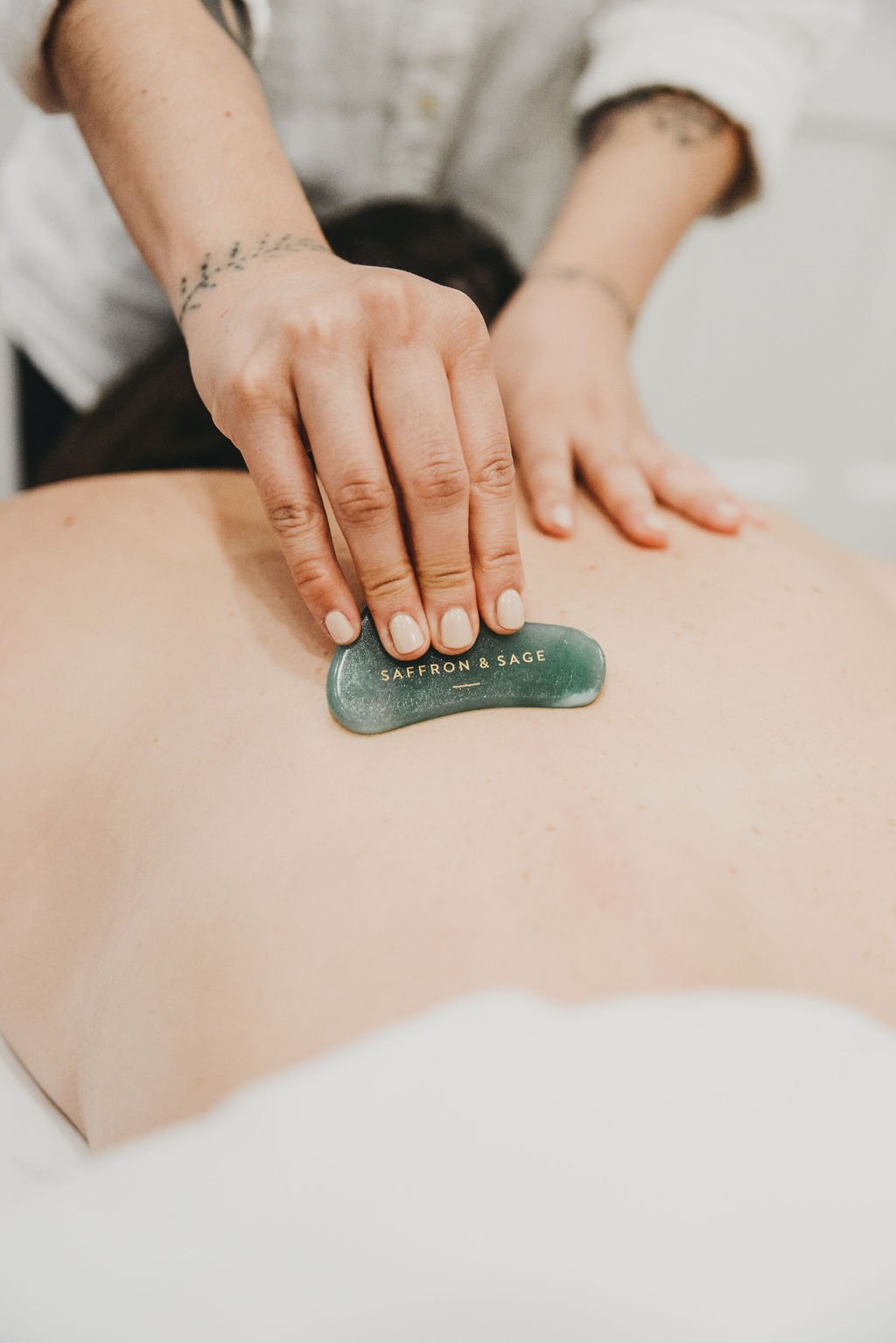 Gua sha along the upper back during an acupuncture session at Saffron & Sage