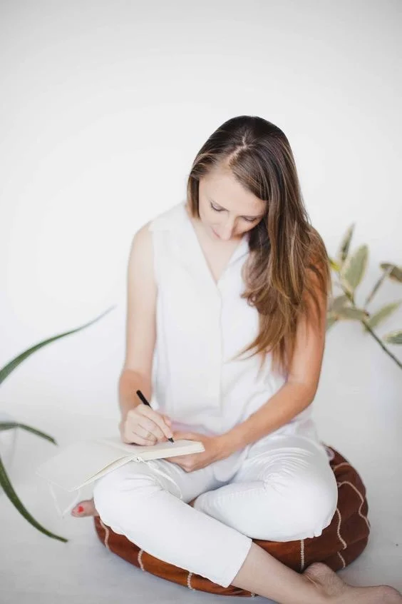 Sitting cross-legged and writing in a notebook