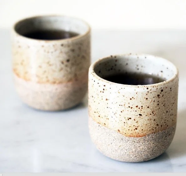 Two speckled ceramic cups of dark coffee, the 3 PM fix that never lasts