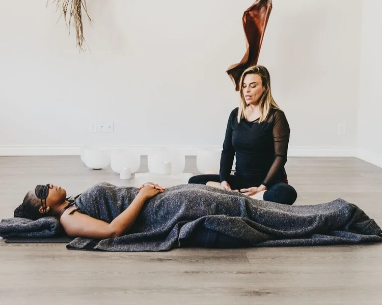 A facilitator guiding a client lying on a mat