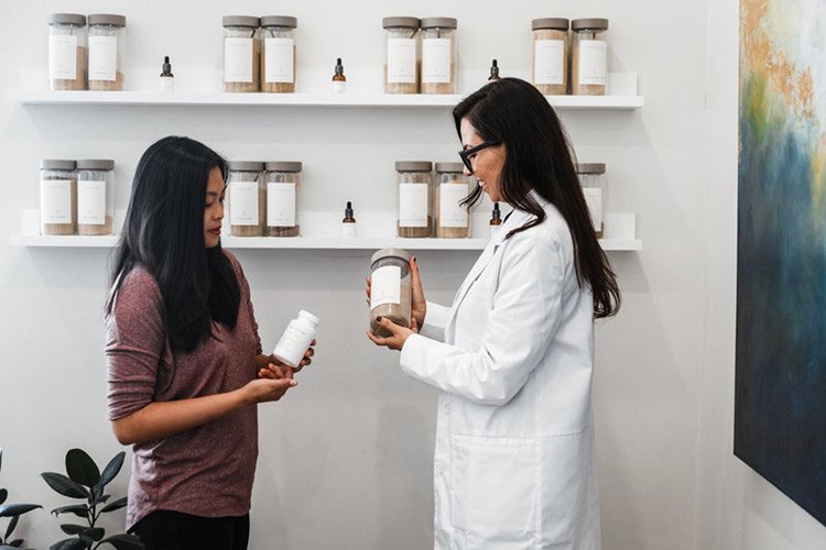 A practitioner and client looking at a bottle in the apothecary