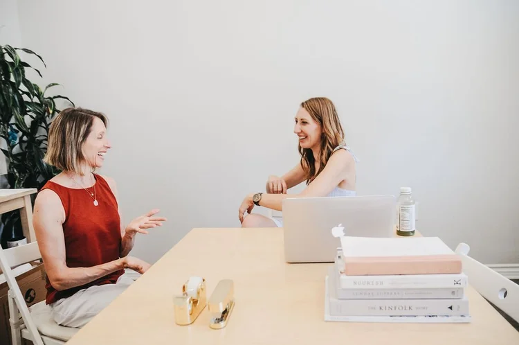 Two colleagues laughing at a desk