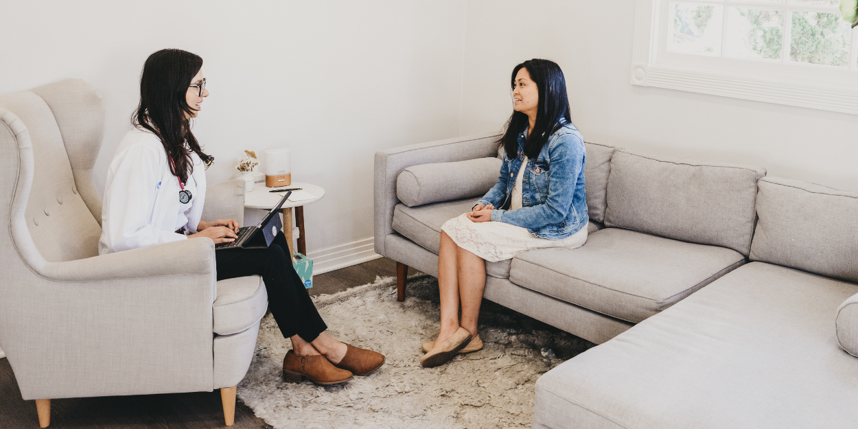 Doctor and patient talking through health history in a calm consultation room at Saffron & Sage, San Diego
