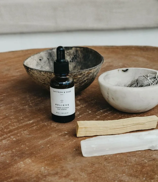 A tincture, sage and selenite on a wooden table