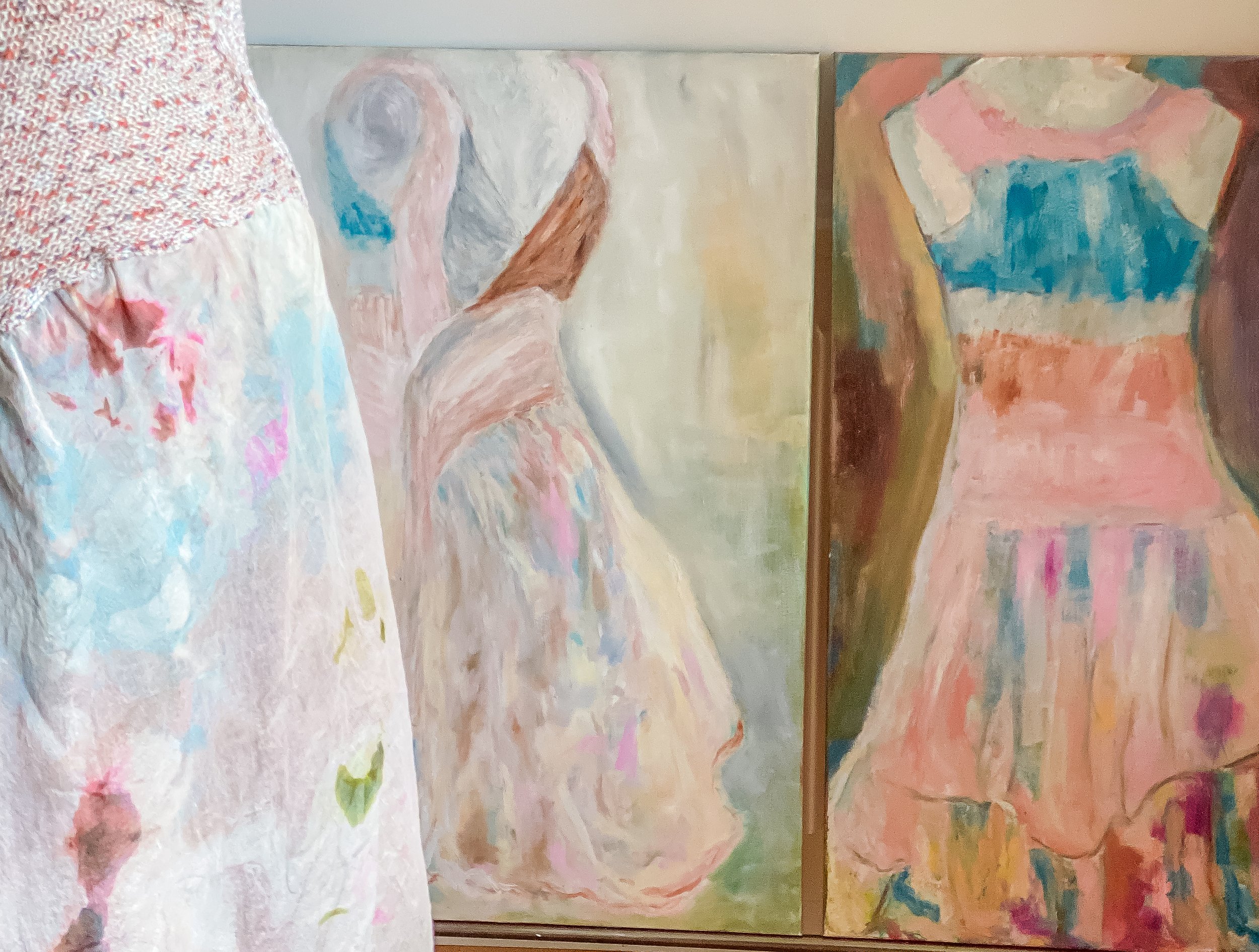 A diptych abstract painting of a female figure wearing a hand painted dress  in pastel colors shown in front of the paintings.