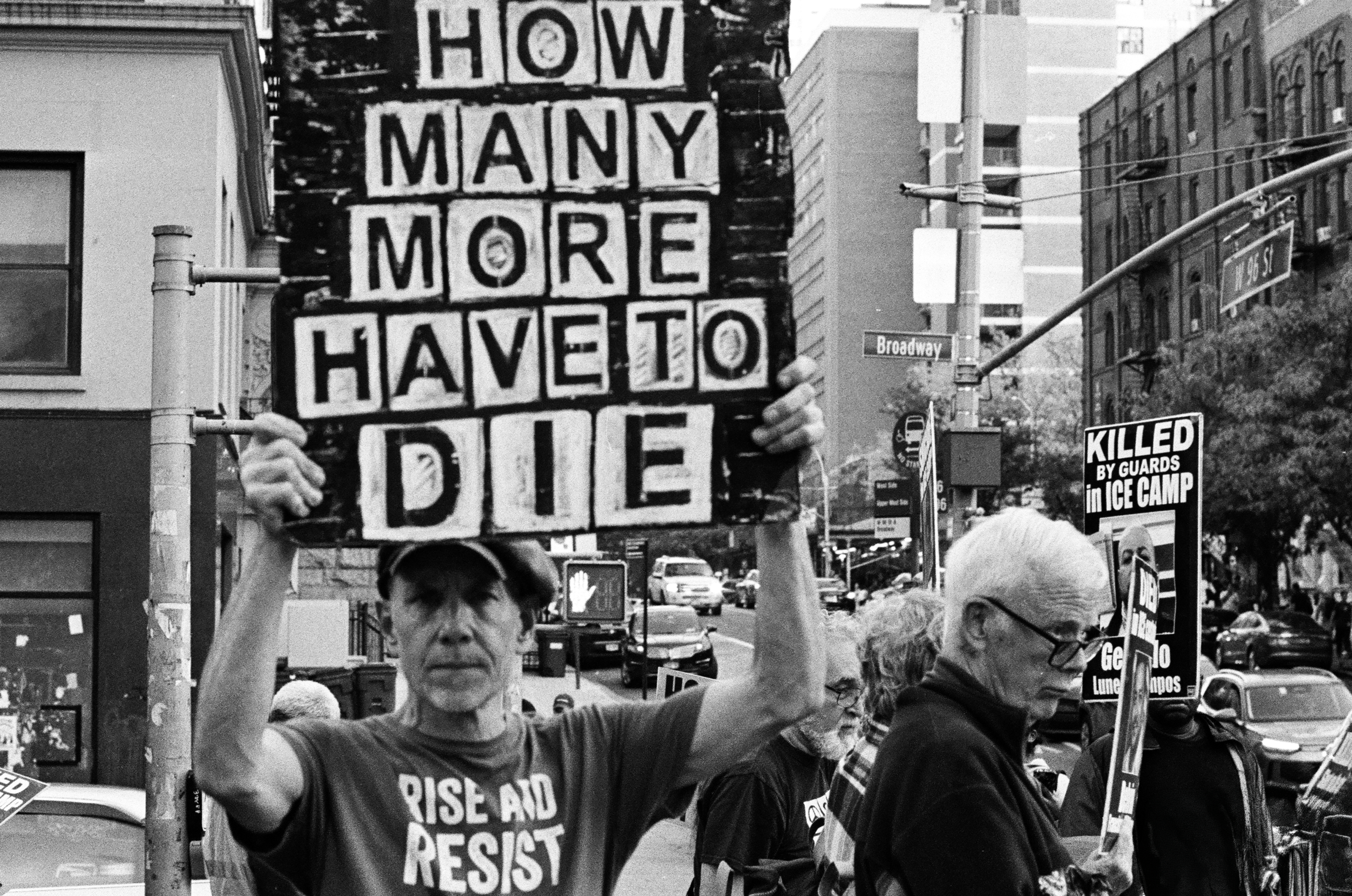 A-Man-Holds-a-Sign-How-Many-More-Have-to-Die.png