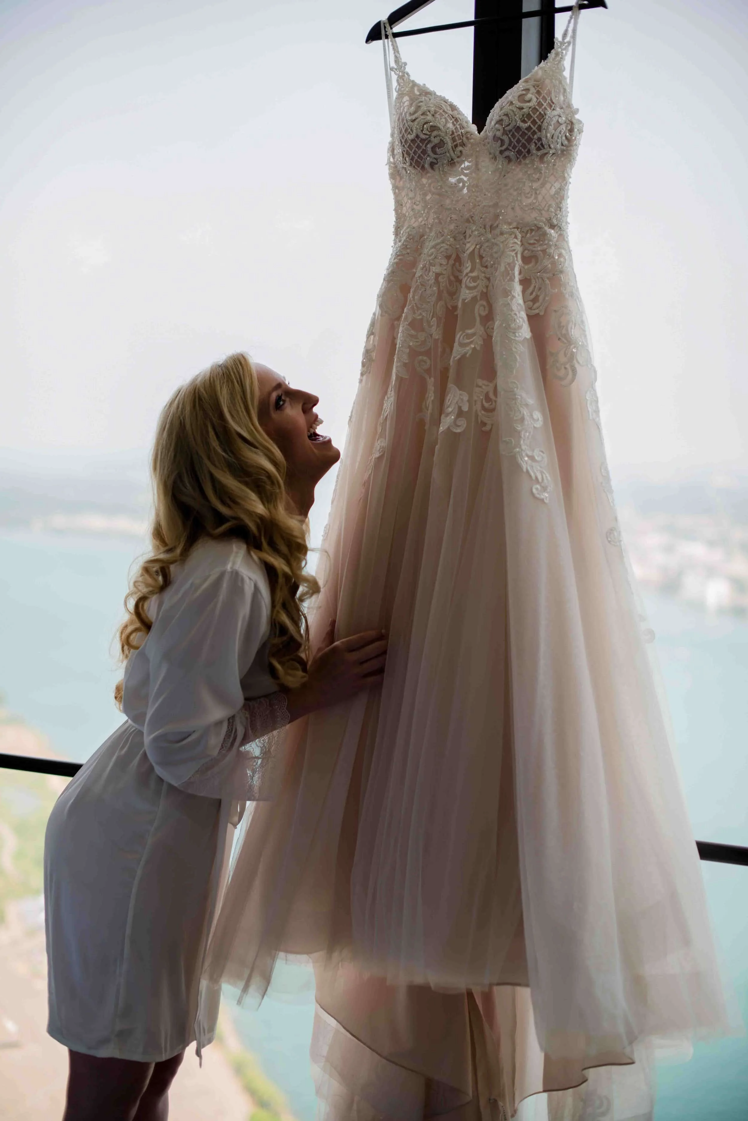 Bride+admiring+her+hanging+gown+in+a+sophisticated+pre-wedding+moment%2C+Detroit+wedding+photographer_compressed.jpg