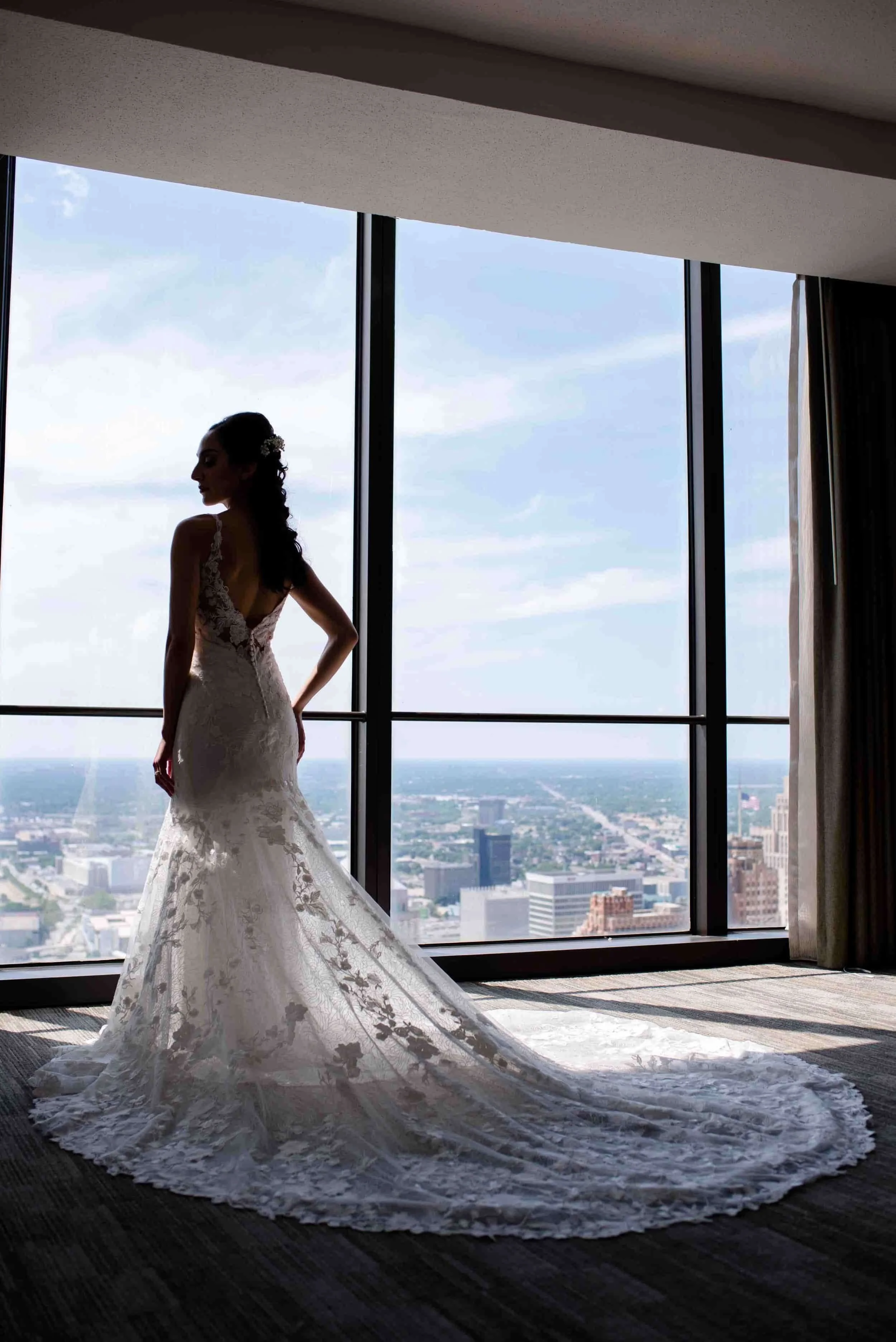 Bride looking out over downtown Detroit from hotel window