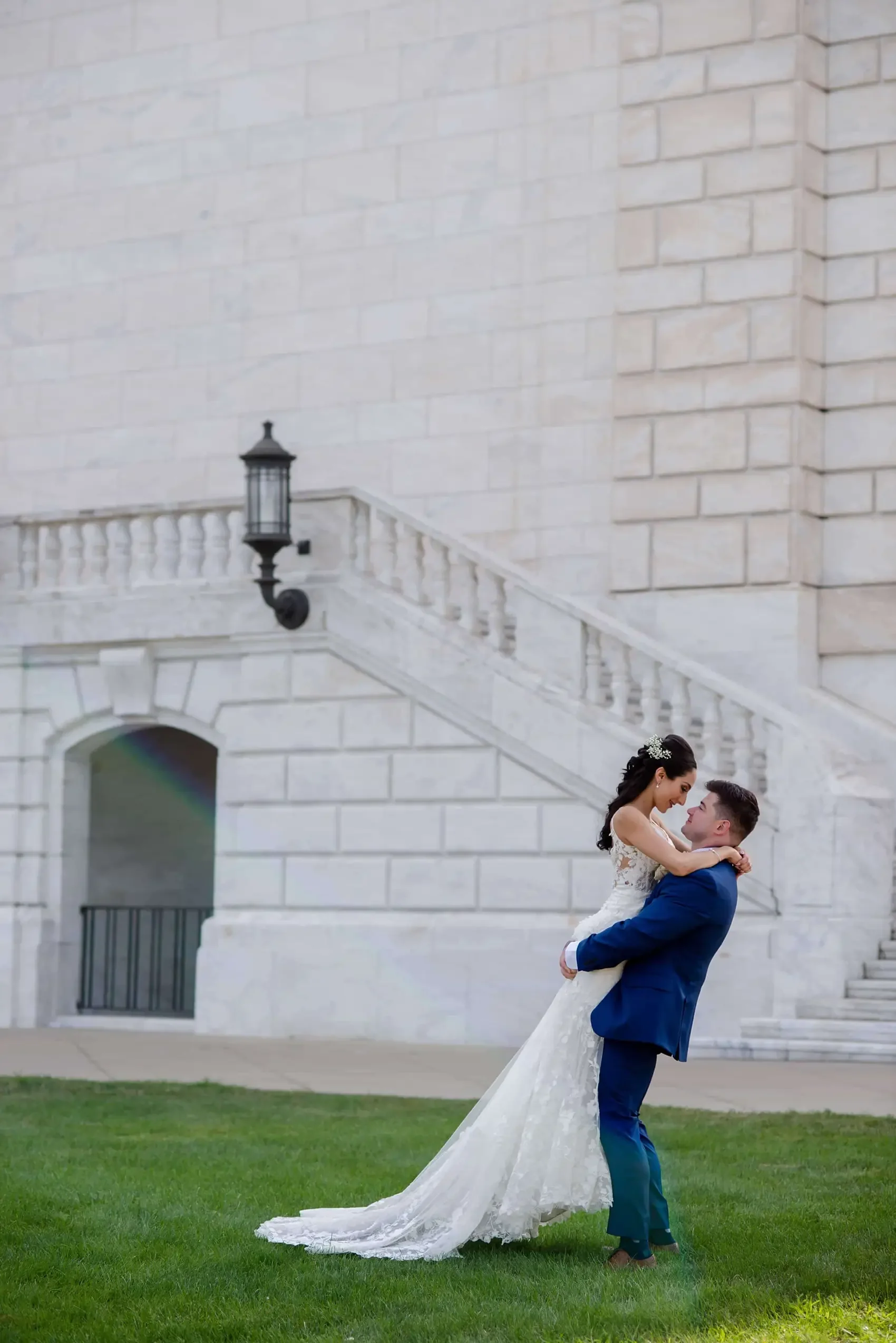 A bride and groom dancing outside near a stone building with stairs and a black lantern.