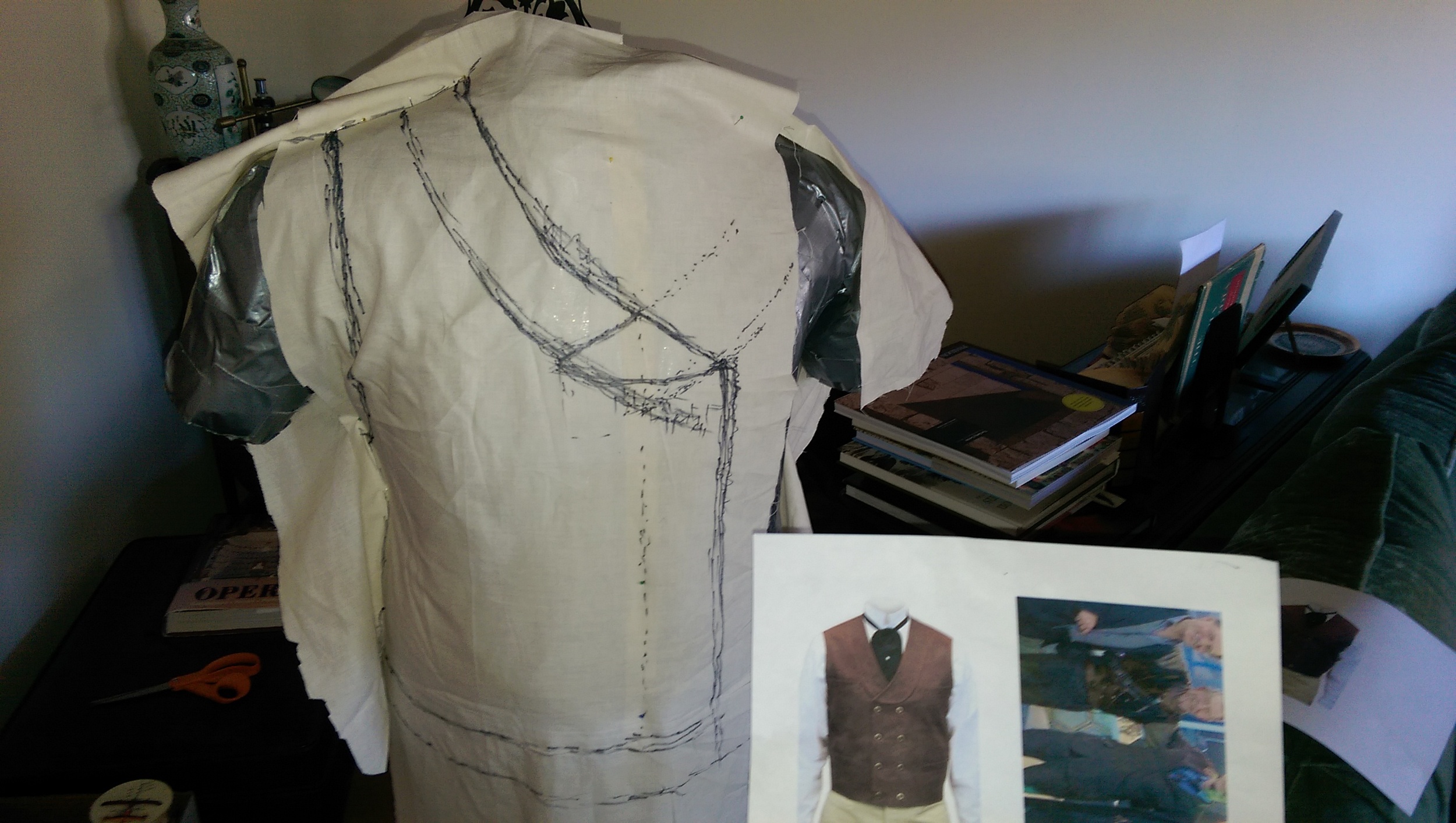 Marking the shape of the waistcoat on muslin that's draped and pinned over the body forrm