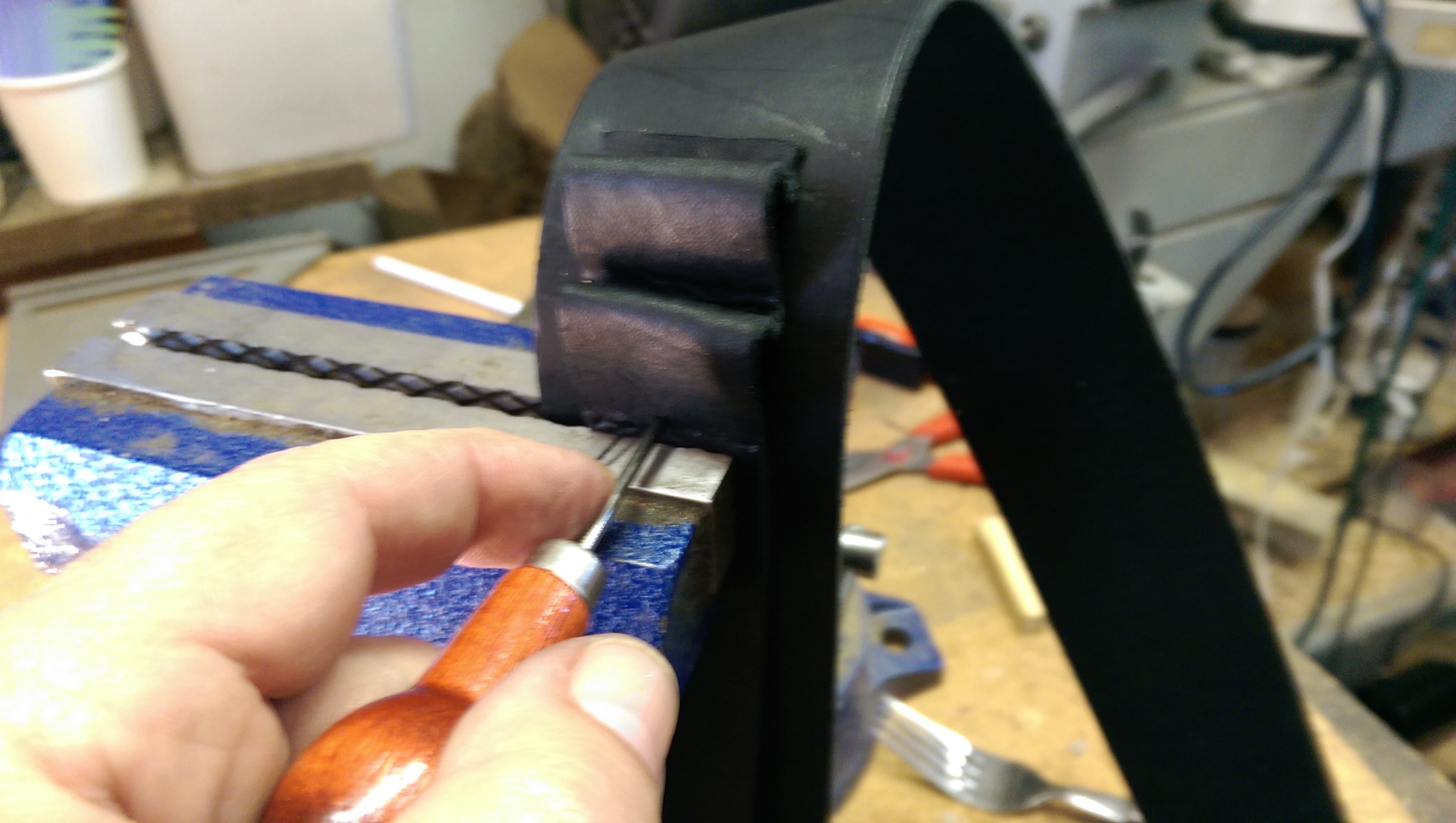 Aligning the spacing lines on the straps and then akligning to the vice jaws in order to punch the stitching holes