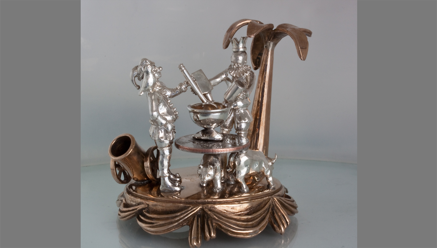 Scene of the jesters creating Artillery Punch on a table made from a 50cent coin. The punch is then brewed in the canon for a week to increase its potency.