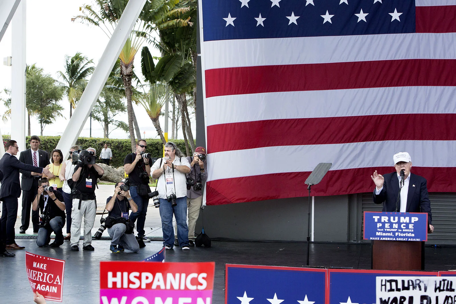 Donald Trump håller ett tal i Miami Florida sex dagar innan presidentvalet. De fotografer som tillhör "traveling press" (de som reser med kandidaten) får komma upp på scenen under några minuter i slutet av talet. De fotograferna, som nästan uteslutande jobbar för de stora amerikanska mediaorganisationerna, får alltid bättre access än de andra fotograferna på plats. Men deras arbetsgivare betalar också ganska mycket pengar för att ha dem med på det specialchartrade flygplanet som gör det möjligt att vara på alla valmöten (för oss som flyger reguljärt är det svårt att hinna med mer än ett möte per dag, speciellt de sista veckorna då kandidaterna har fyra fem valmöten per dag i olika delstater.