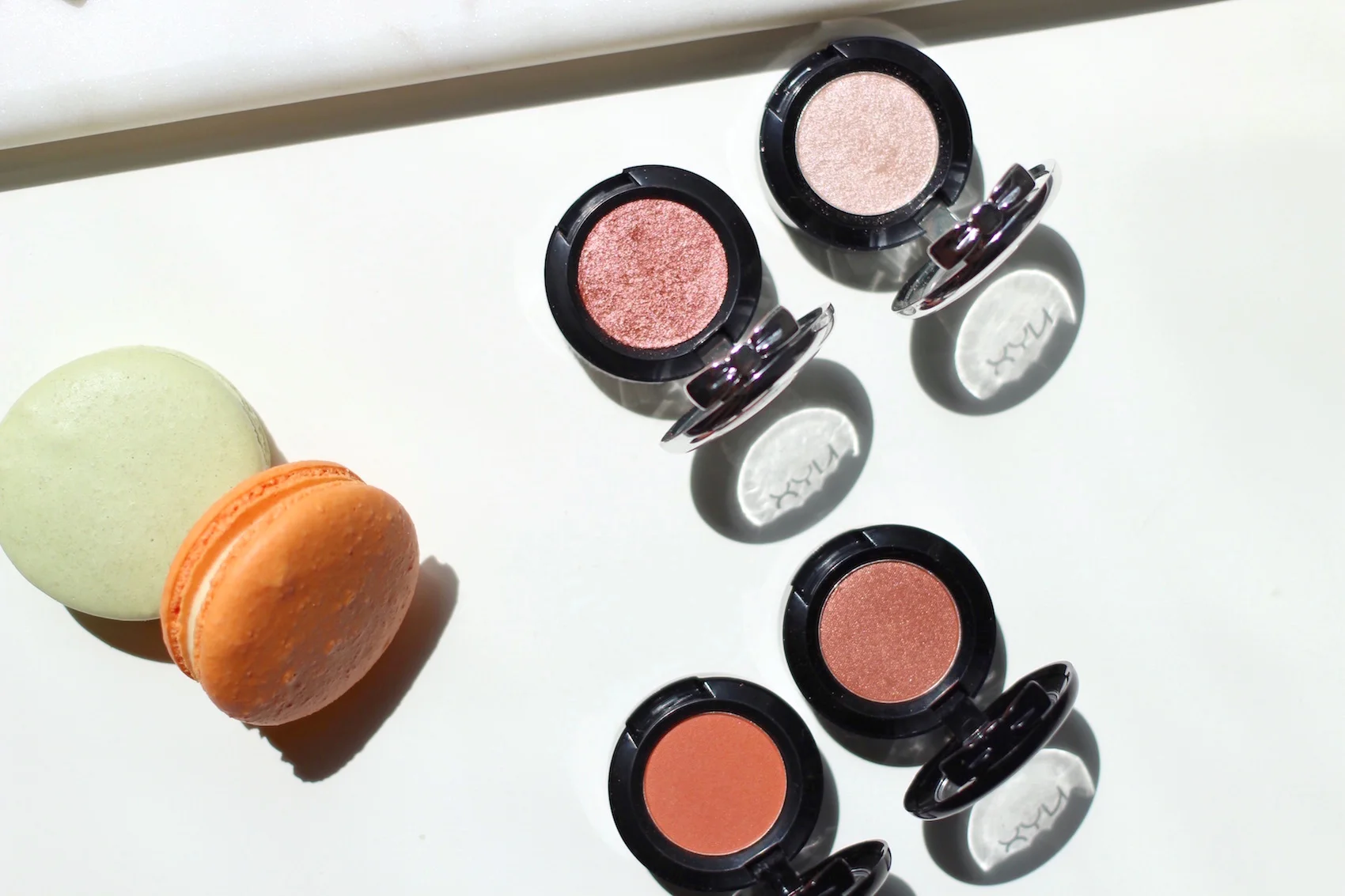Top row: NYX Prismatic Eye Shadows in Fireball (an orange-rose metallic shade) and Girl Talk (a pale pink metallic shade, perfect for highlighting when used lightly). Bottom row: NYX Hot Singles Eye Shadows in LOL (matte orange) and Showgirl (metallic rusty orange).