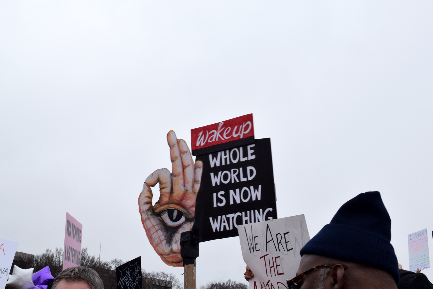 A sign says "the world is now watching"