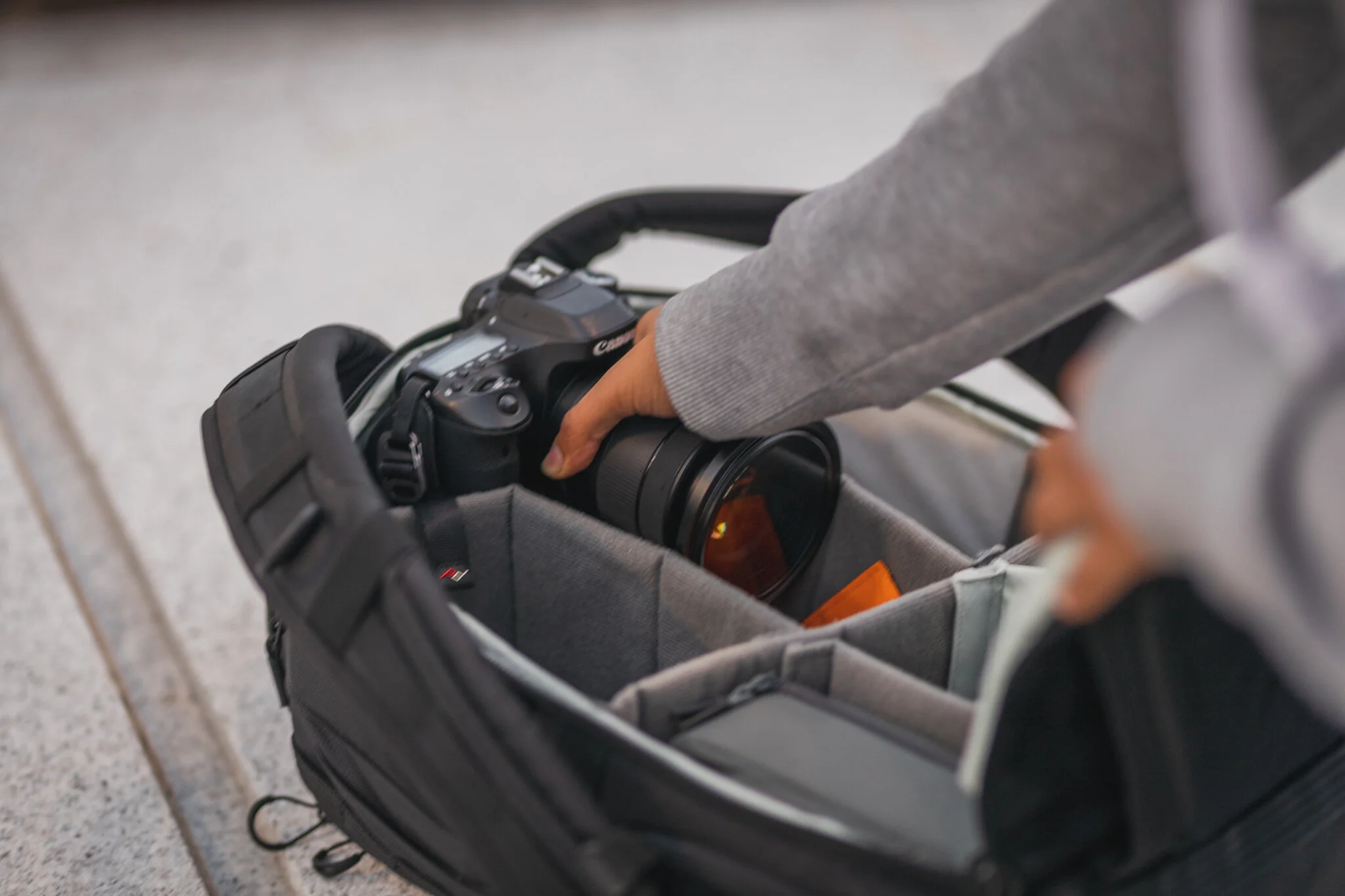 A person who is completing a photography course leaning into a bag and picking up a camera