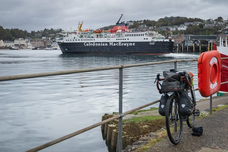 A bike leaning against a fence with a Calmac ferry in the background