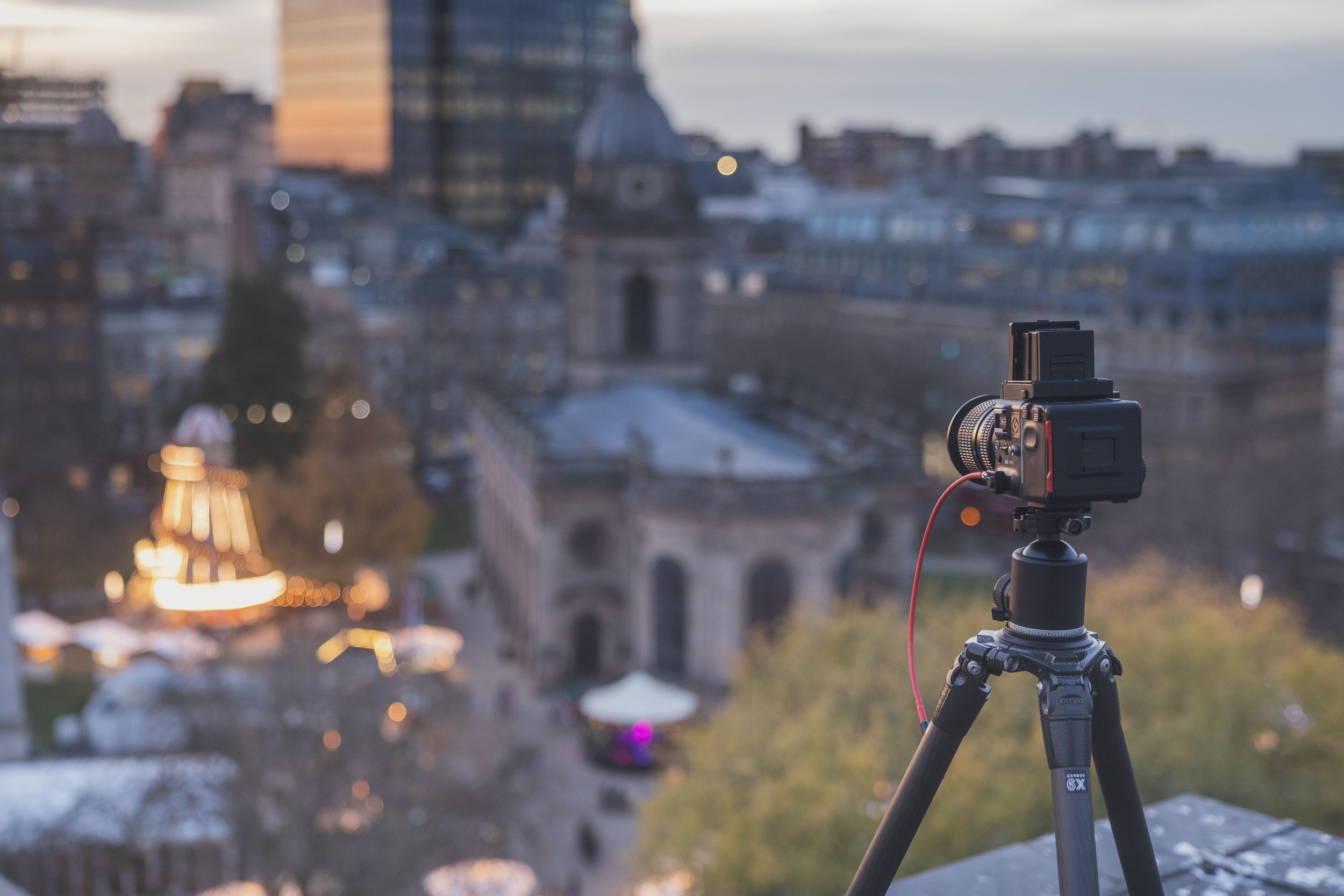 A camera on a tripo on a roof with a skyline view