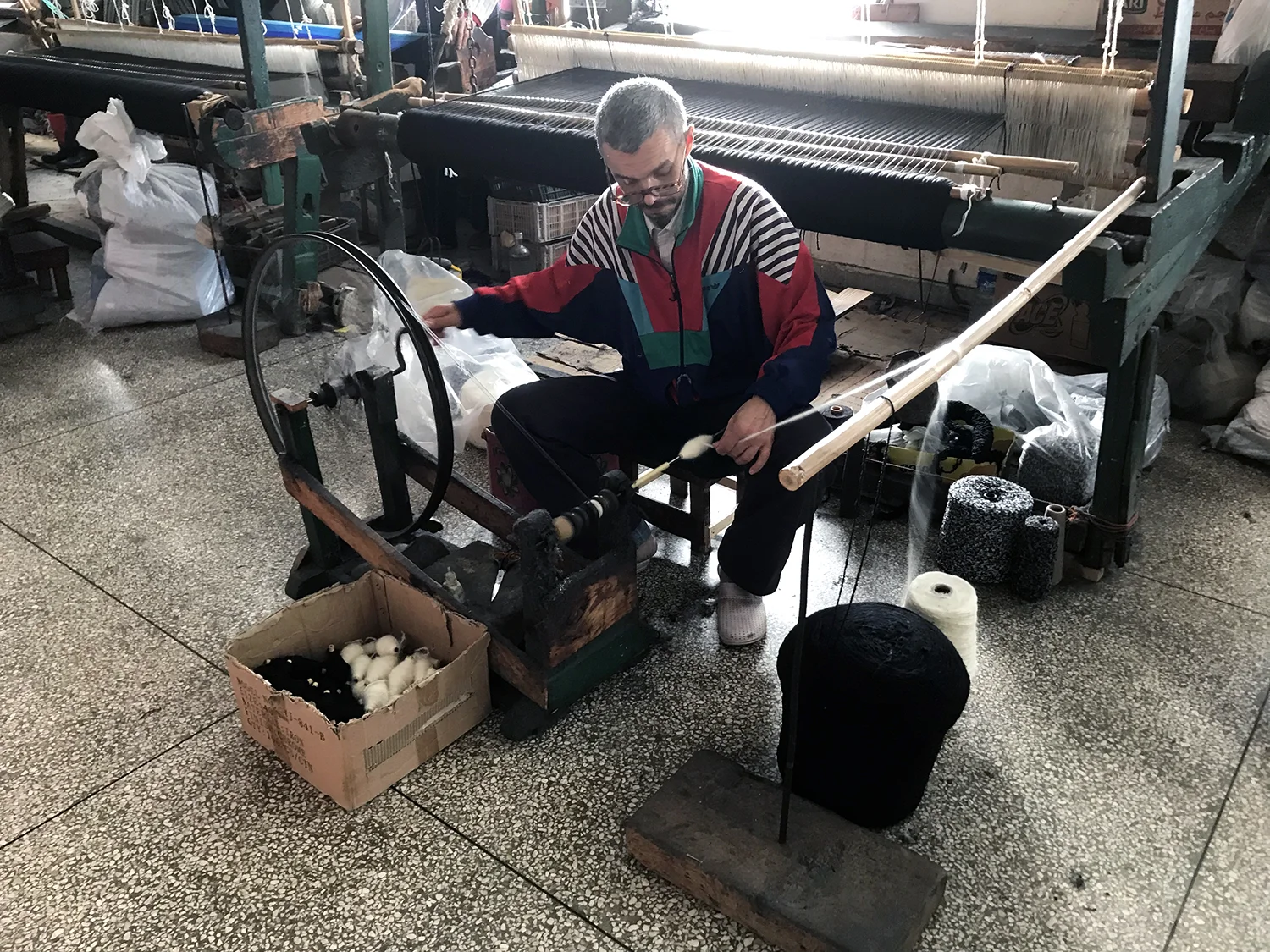 A weaver loading the bobbin with the spinning wheel.