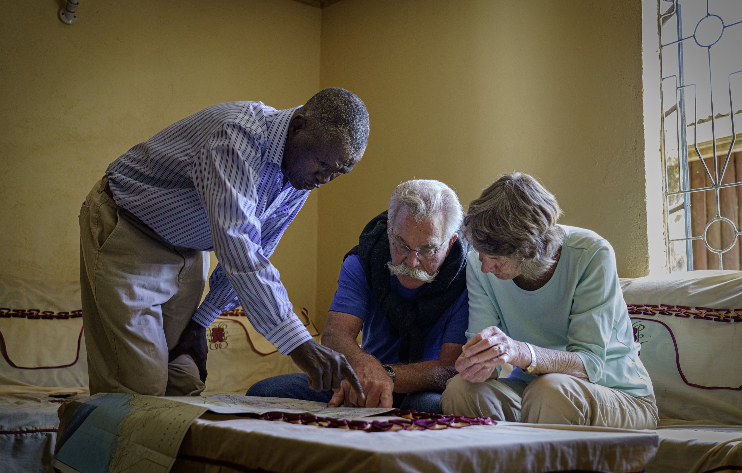 Josphat, Bill, and Louise Johnston review a map of Kenya