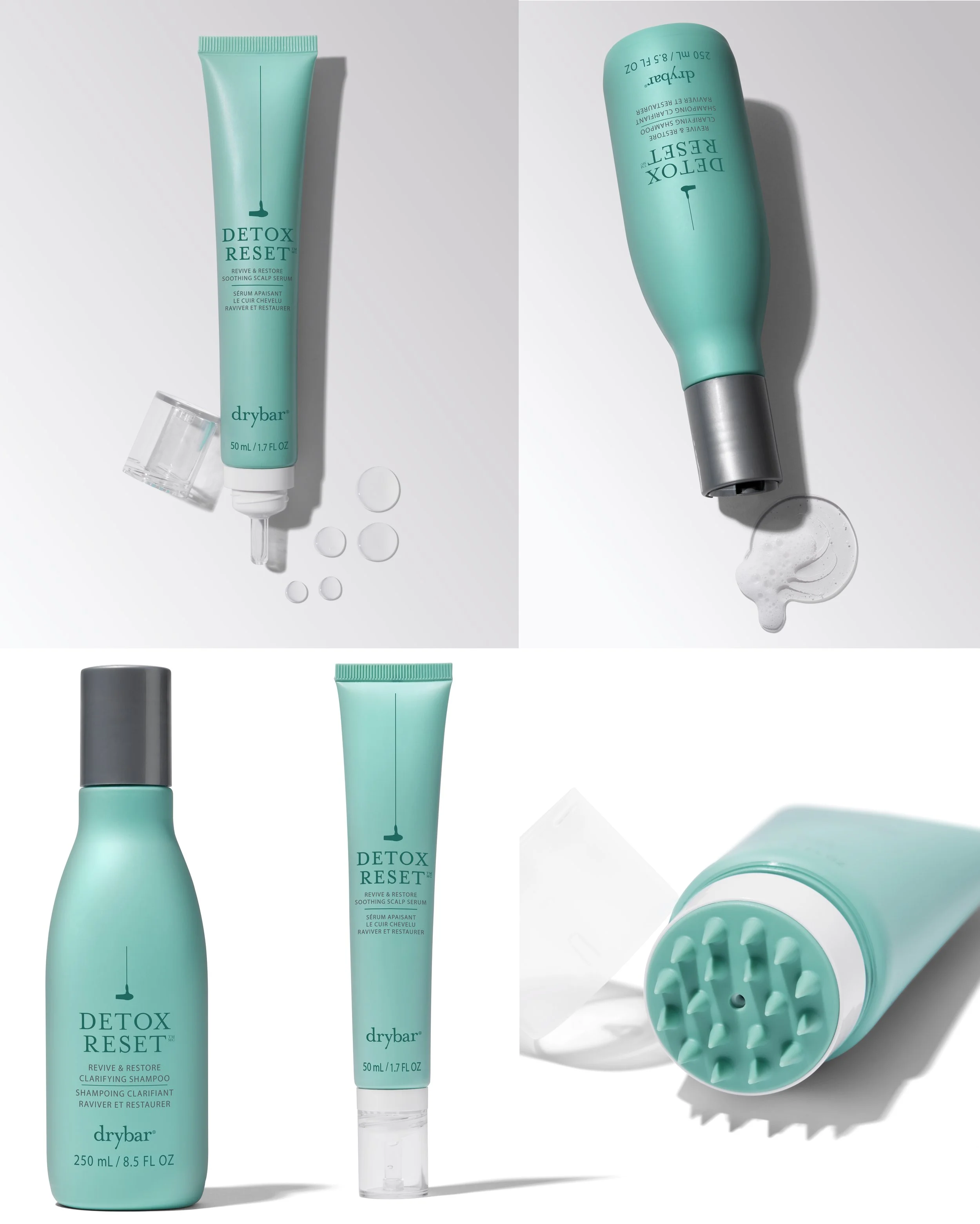 A collection of haircare products, including a tall, light blue bottle labeled 'Detox Reset' drybar shampoo, a small tube labeled 'Detox Reset', and a white and teal scalp massage brush. Some liquid and foam are spilled around the products.