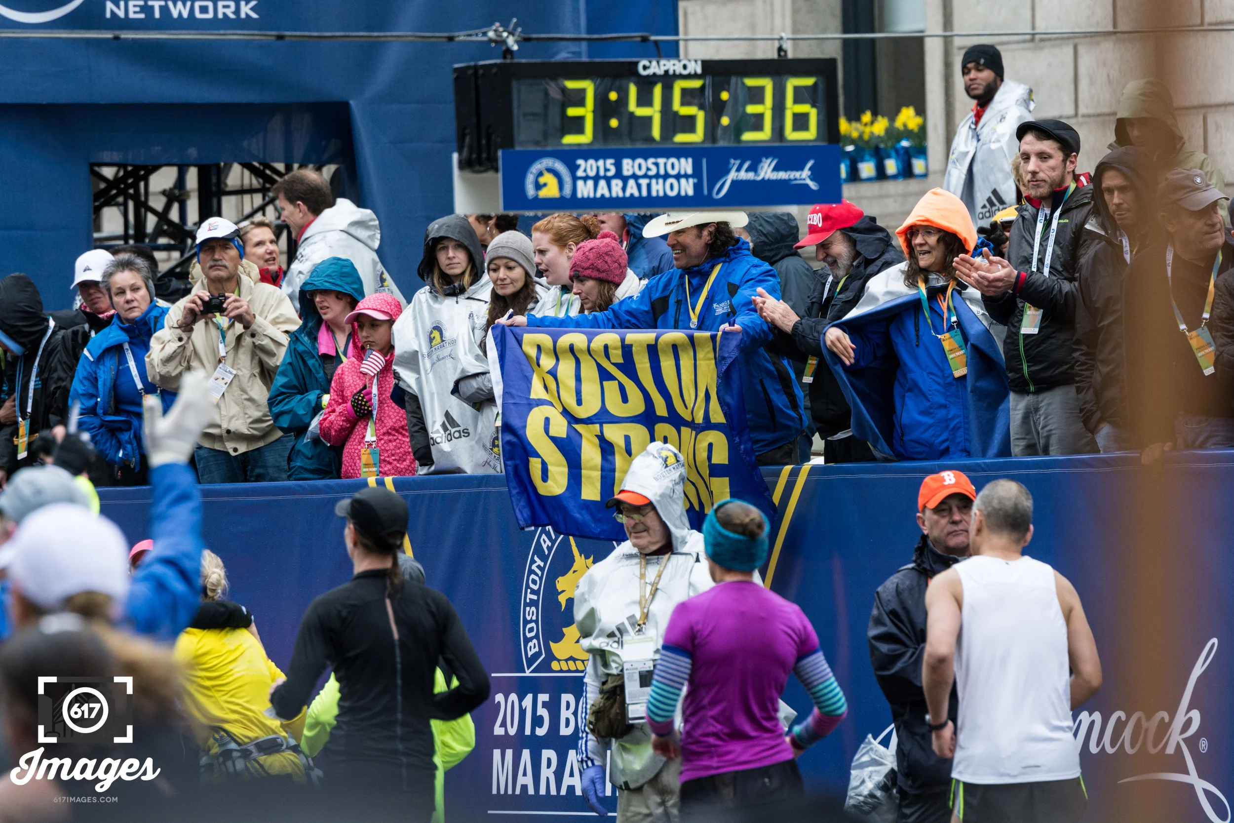 Carlos Arredondo waves his Boston Strong flag as runners cross the finish line.