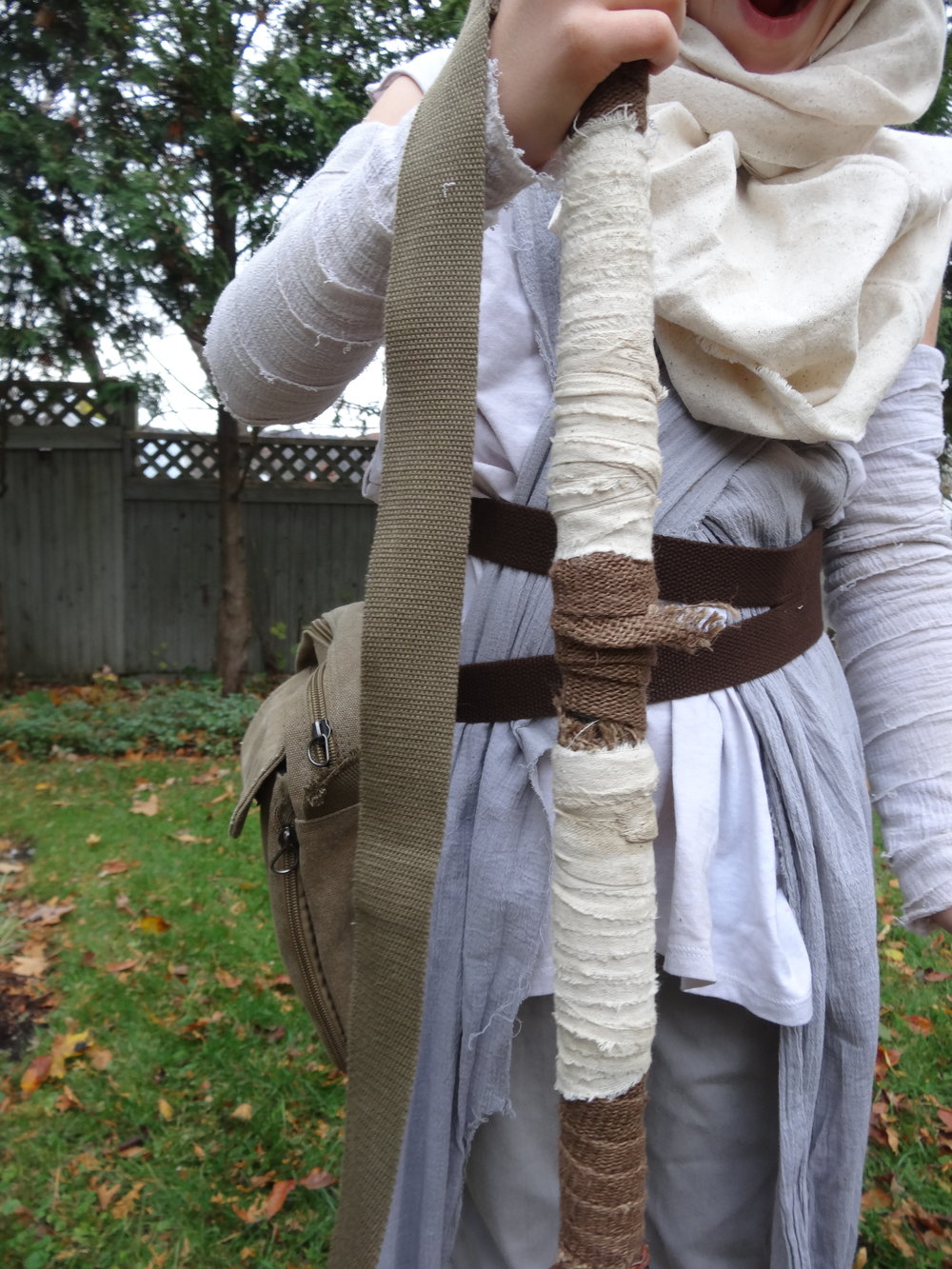  Staff: Curtain rod, spray painted and wrapped in gauze and burlap with a handle from the bag on her belt.  Belt: Belt webbing sewn together on the left and clipped together under the bag on the right. 