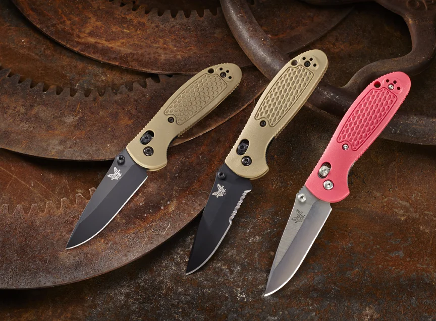 Benchmade Knife Co. folding knives displayed on rusted gears. 
