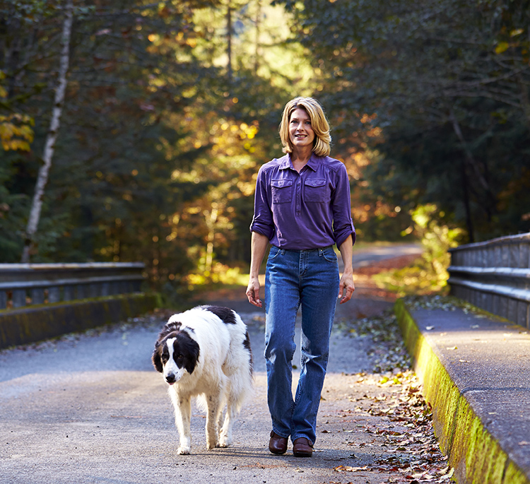 Woman wearing active wear, walking with large breed dog. 