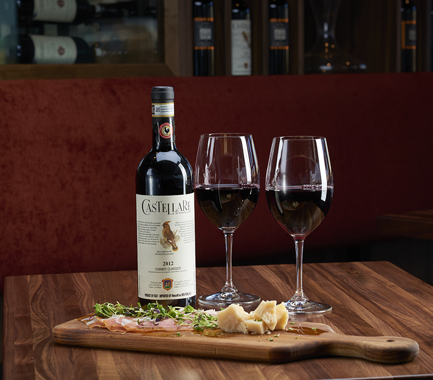 Filled wine glasses with a bottle of wine and appetizer. 