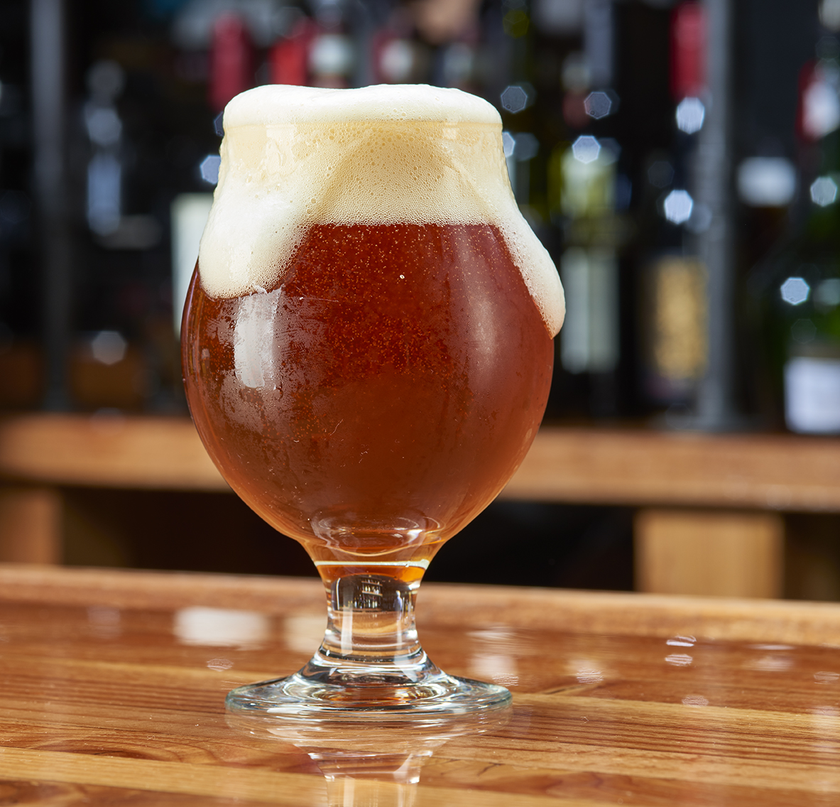 Foaming beer on wood bar top. 