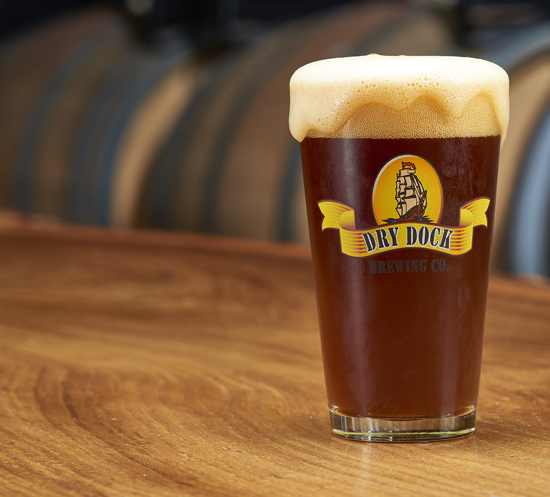 Glass of Dry Dock beer on wood bar counter. 