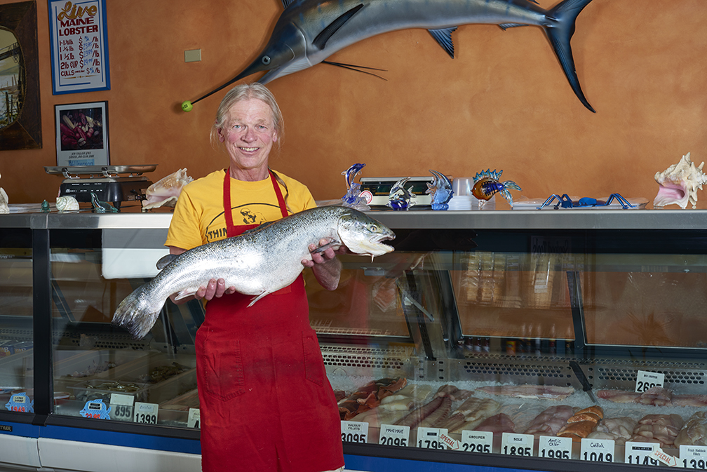 Fishmonger holding large fish at local market in Denver, Colorado. 