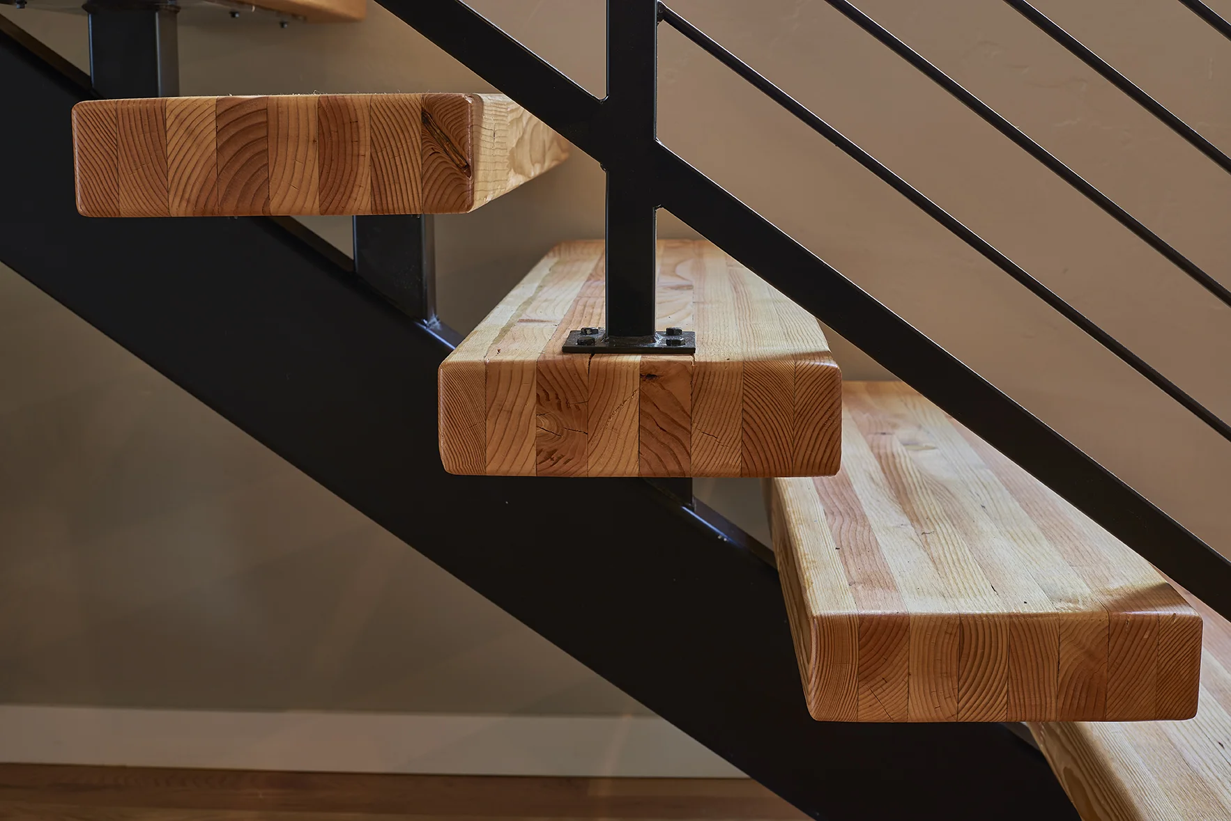 Floating butcher block stair treads with black iron railing.